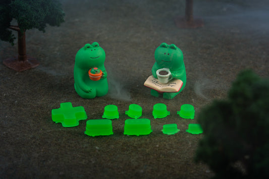 two frog figures sitting in a forest next to lime green steam deck buttons