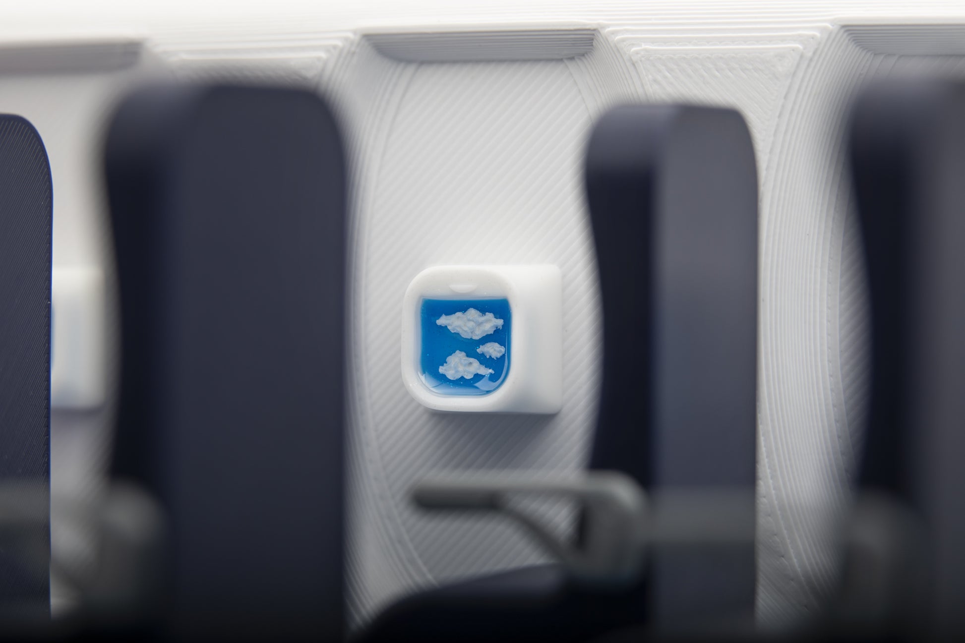 Airplane window keycap shows clouds and blurry airplane seats in foreground