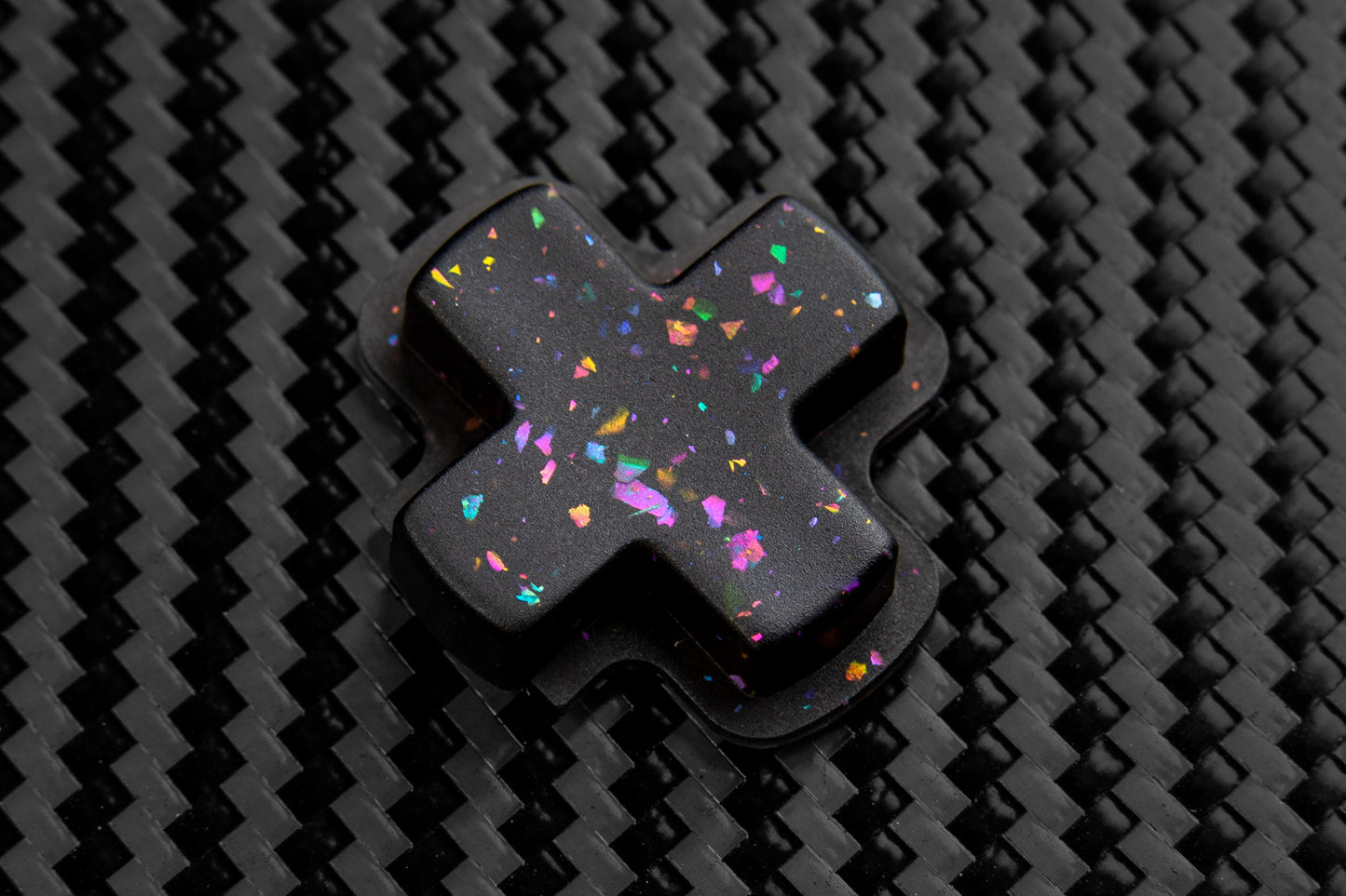 Close up of dpad on carbon fiber background. Party black metallic shards of color mixed into black buttons.