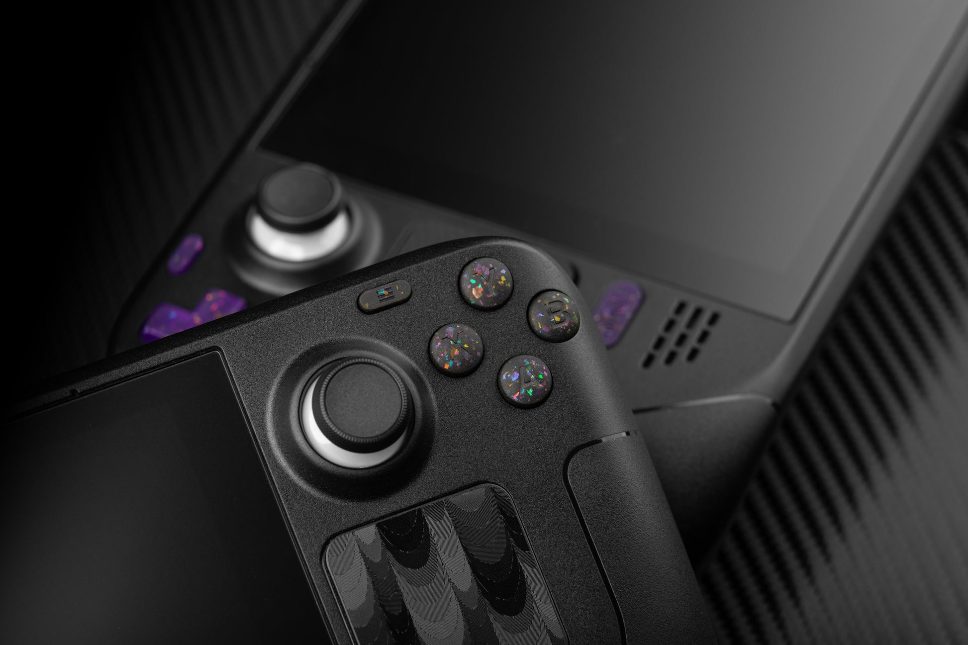 steam deck with party black abxy buttons leaning against a steam deck with purple buttons installed