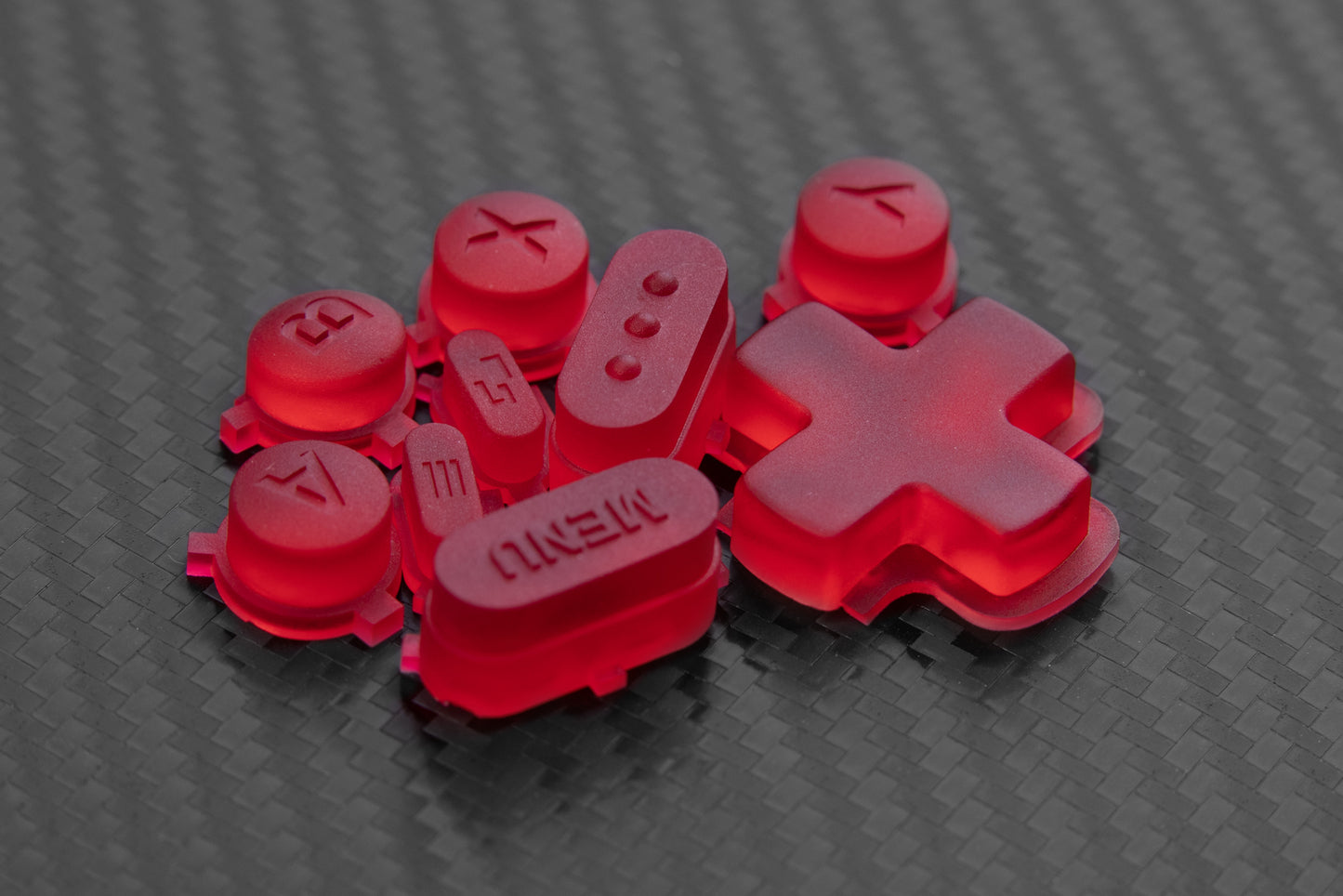 Red steam deck button set loosely in a pile on top of carbon fiber