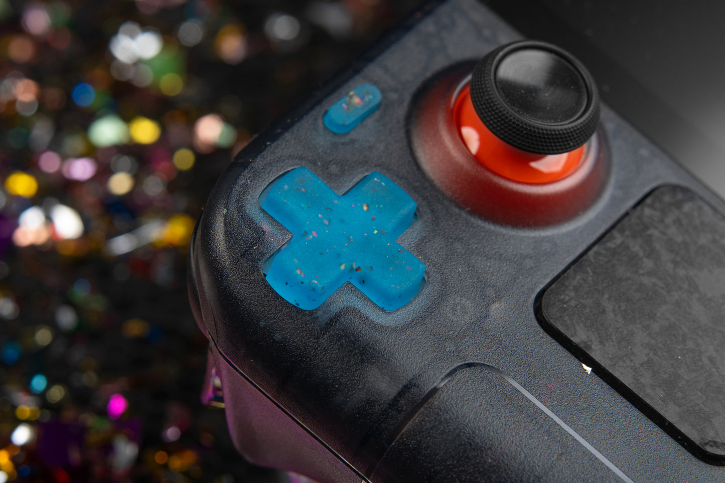 close up of a party blue steam deck dpad installed. Confetti background.