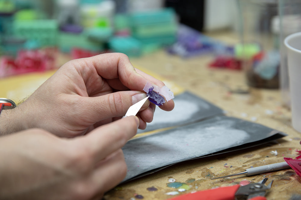 Image showing cutting the back of a steam deck button fresh from the mold