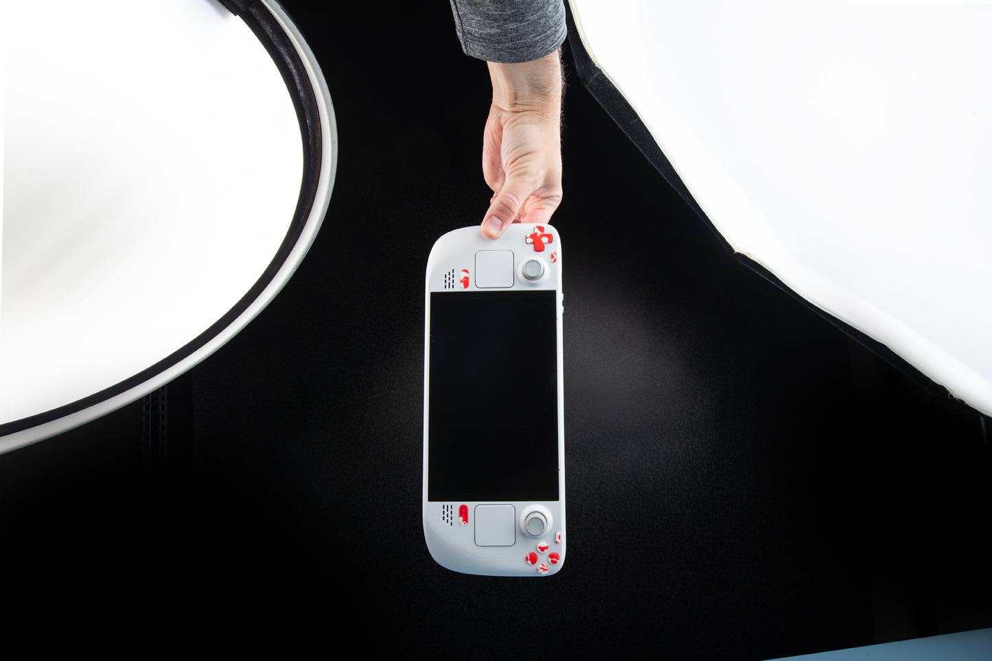 limited edition white steam deck with blood splat buttons, wide angle shot with hand dangling the steam deck