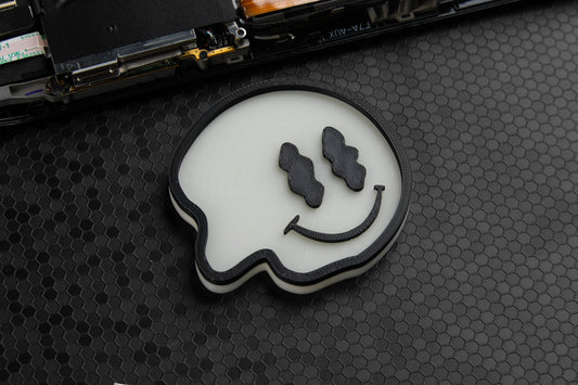 Glow in the dark screw tray on a black hex background. Smiley face shaped.