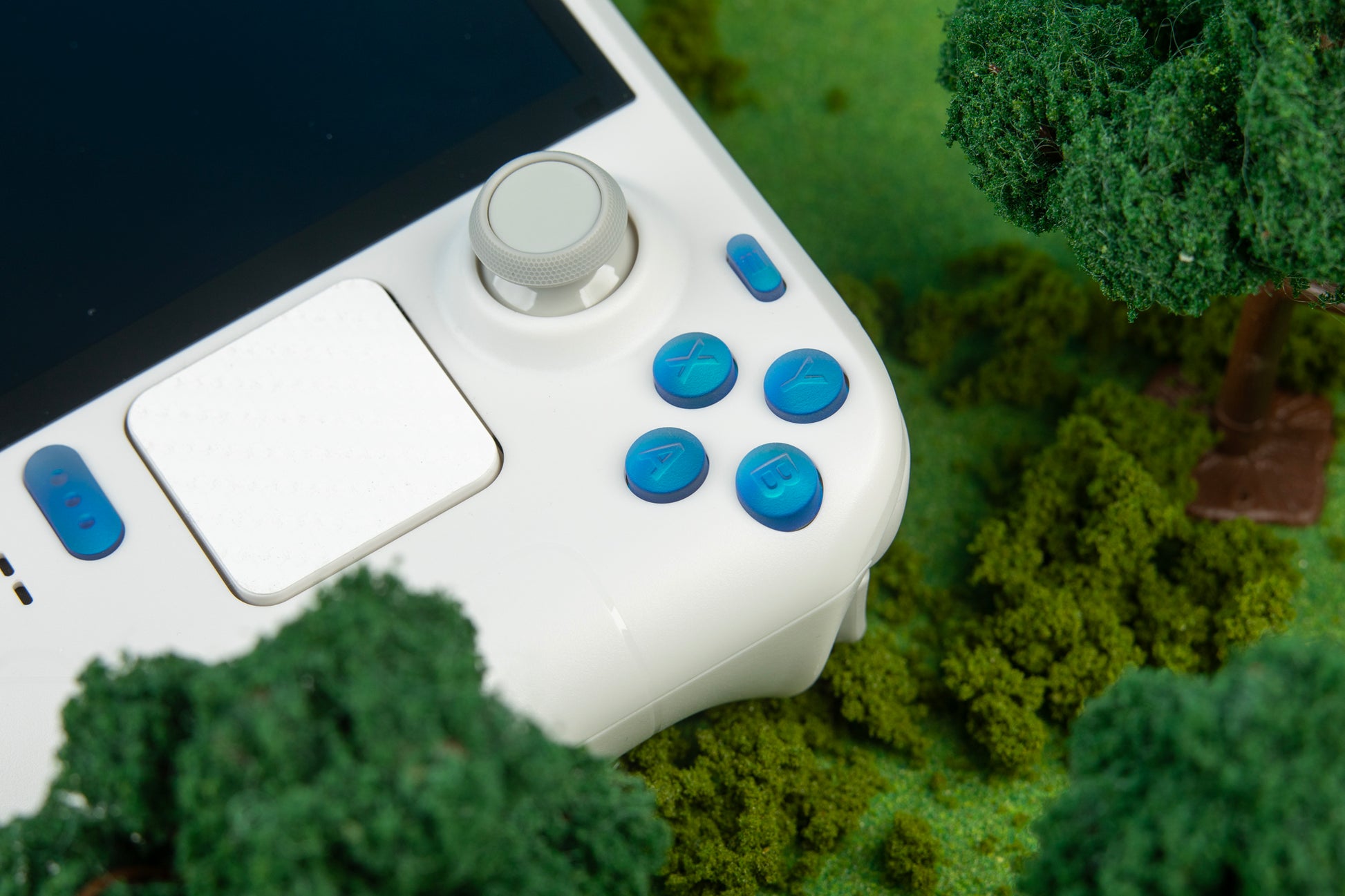 White steam deck with holographic blue buttons on a grassy background