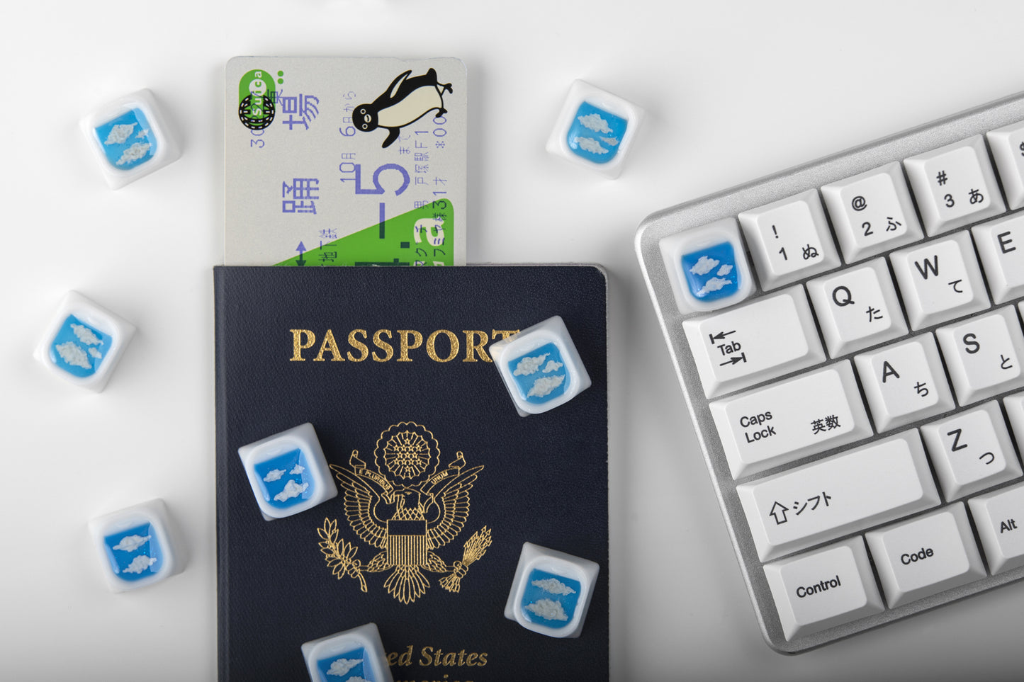Airplane window keycaps shown on top of a passport and keyboard to the right