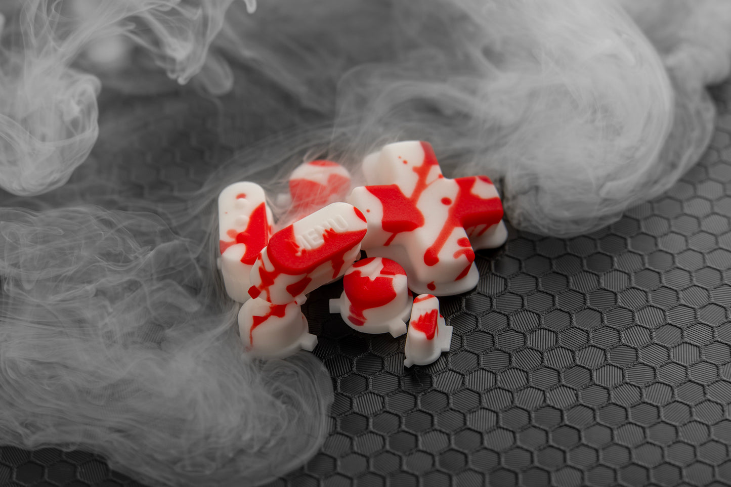 Blood splat steam deck buttons loosely in a pile with fog. Honeycomb background. 