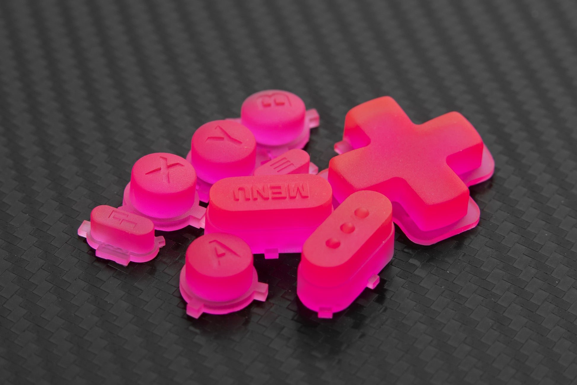 Steam deck buttons bright transparent neon pink in a pile on carbon fiber background