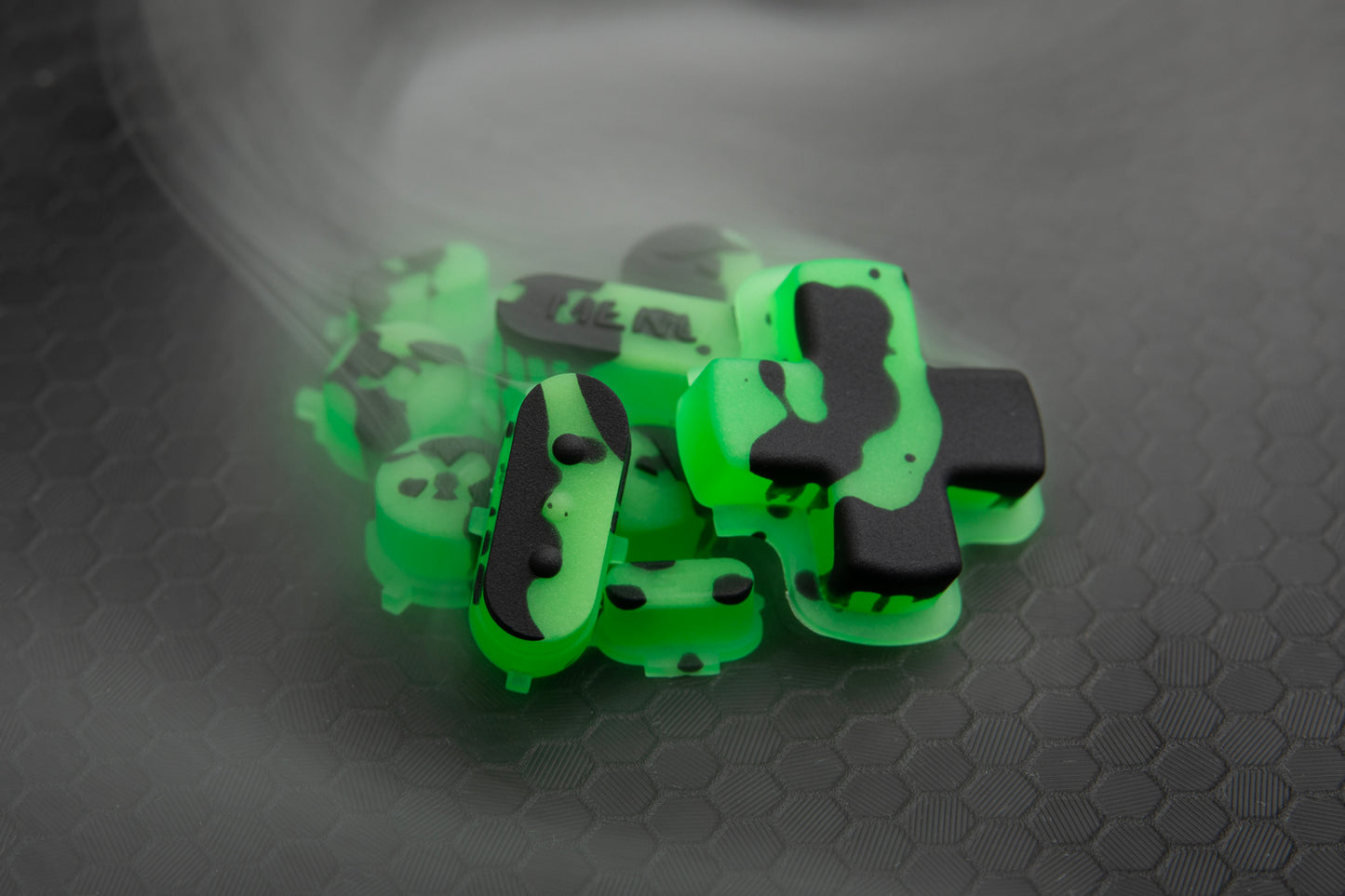 close up steam deck buttons in a loose pile. Green and black splat theme with fog surrounding