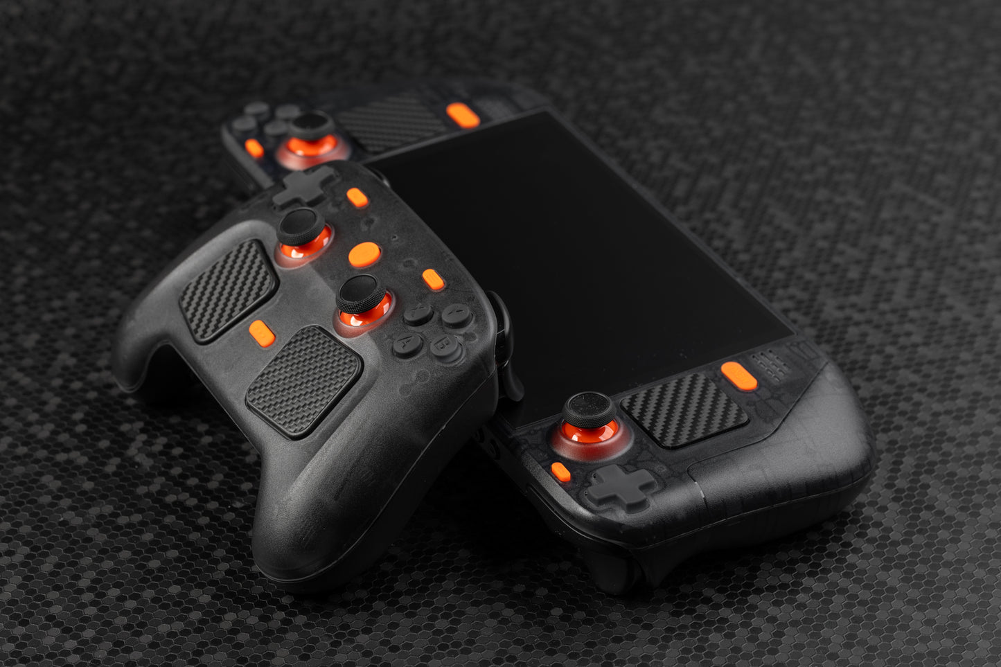 side view of steam controller leaning on steam deck. Both have a smoked black housing with orange accent buttons